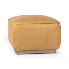 a tan leather ottoman with wooden legs and footrests on an isolated white background