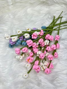 small pink and white flowers laying on top of a fur covered floor next to each other