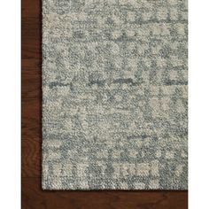 an area rug that is on top of a wooden floor with a white and blue pattern