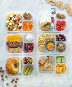 several plastic containers filled with food on top of a white countertop next to fruit and crackers