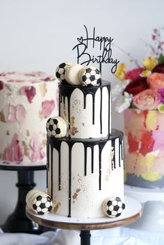 two birthday cakes with soccer themed frosting sitting on top of each other, one is white and the other is black