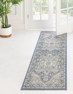 a large blue rug is on the floor in front of a white door and potted plant