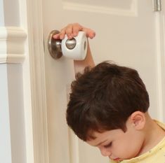 a young boy is opening the door with an electronic device in his hand and looking at it