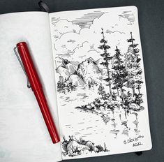 a pen is sitting on top of a notebook with a landscape drawn in it and some trees