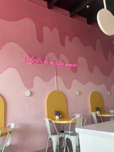 a restaurant with pink walls and yellow chairs