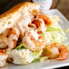 a sandwich with shrimp and lettuce is on a plate next to a bottle of mayonnaise