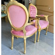 two pink and gold chairs sitting next to each other