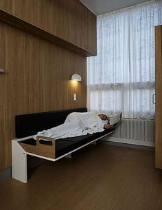 a bed sitting in a bedroom next to a window with curtains on the windowsill