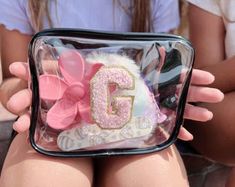 a woman holding a clear bag with pink and white decorations on it's side