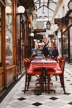 people are sitting at tables in the middle of an alleyway with checkered tablecloths