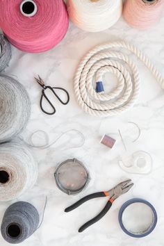 several different types of yarn and scissors on a white marble surface with various colors of thread