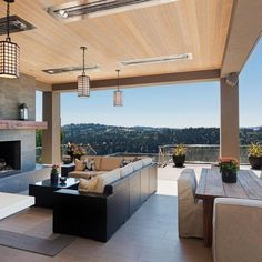 an outdoor living area with couches, tables and chairs on the patio overlooking trees