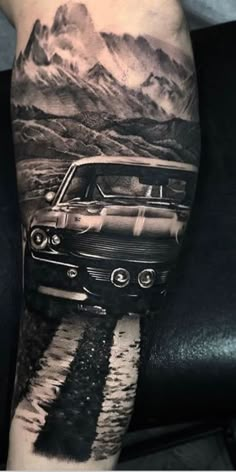 a black and white photo of an old car on the side of a man's leg