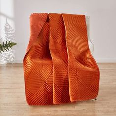 an orange chair sitting on top of a hard wood floor next to a christmas tree