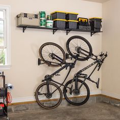 there is a bike hanging on the wall in this room with other bikes and tools