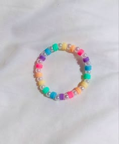 a bracelet with multicolored beads is laying on a white sheet