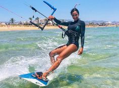 a woman in a wet suit is on a surfboard with a parasail