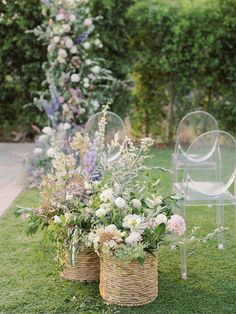 two wicker baskets filled with flowers sit on the grass next to an empty chair