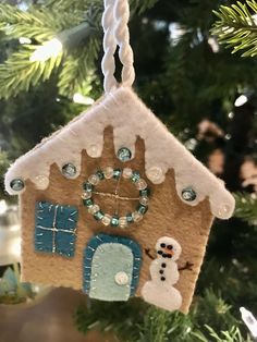 a christmas ornament hanging from a tree with a house and snowman on it