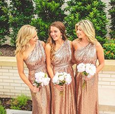 three women in gold dresses standing next to each other and one is wearing a flower bouquet