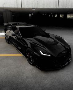 a black sports car is parked in a parking lot with yellow lines on the ground