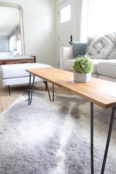 a living room with a white couch and wooden table in the middle, along with a rug on the floor