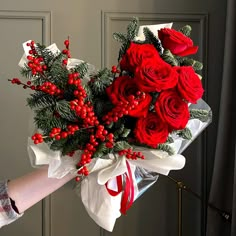 a bouquet of red roses and greenery wrapped in white paper