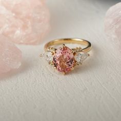 a pink diamond ring sitting on top of a table