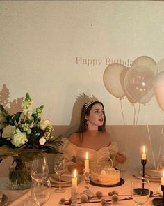 a woman sitting at a table in front of a birthday cake with candles on it