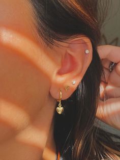 a close up of a person wearing some kind of earring with a heart on it