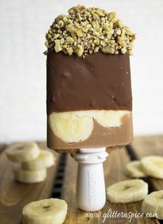 an ice cream bar with chocolate and banana slices on top, surrounded by sliced bananas