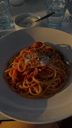 a plate of spaghetti with sauce and parmesan cheese on top, sitting on a table