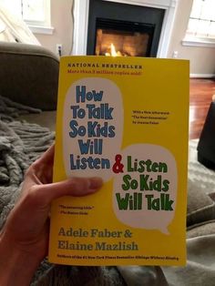 a person holding up a book in front of a fireplace with the title how to talk so kids will listen and go kids will talk