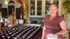 a woman standing in front of a counter filled with jars