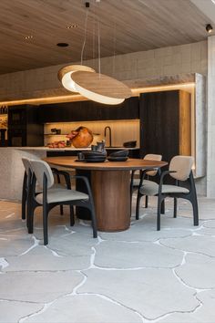 a dining room table surrounded by chairs and an oval shaped light hanging from the ceiling