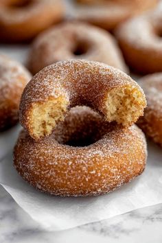 several sugared doughnuts sitting on top of white paper