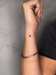 a woman's arm with a small heart tattoo on the left side of her wrist