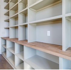 an empty room with white shelving and wooden shelves on the wall, in front of a door