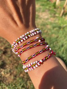 a person's arm with several different bracelets on top of it, in the grass