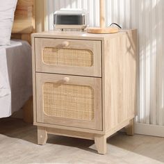 a wooden nightstand with two drawers and a microwave on top of it next to a bed