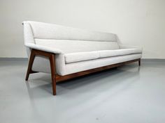 a white couch sitting on top of a hard wood floor next to a gray wall