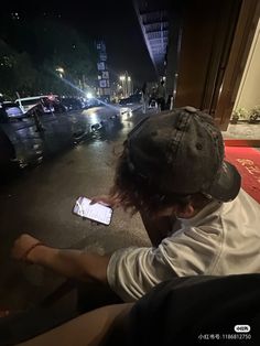 a person sitting on the ground with their cell phone in front of them and looking at it