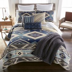 a bed covered in blue and white pillows