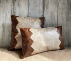 two brown and white pillows sitting on top of a wooden floor next to each other