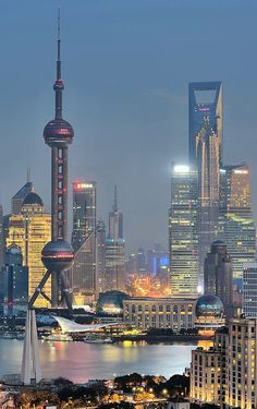 the city skyline is lit up at night, with skyscrapers in the foreground