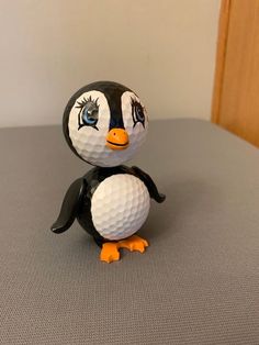 a black and white penguin figurine holding a golf ball