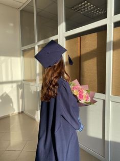 a woman in graduation gown and cap holding flowers