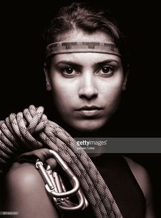 a young woman holding a rope and looking at the camera with an intense look on her face