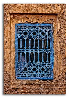 a blue window on the side of a building with iron bars in front of it