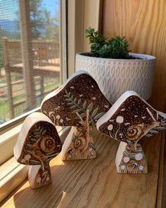 three ceramic mushrooms sitting on top of a wooden table next to a potted plant